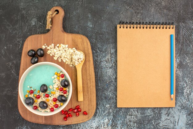 Bovenaanzicht bessen havermout druiven zaden van granaatappel lepel op het bord notebook potlood