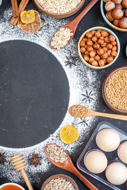 Bovenaanzicht bestrooide bloem cirkel kommen met haver tarwe granen noten houten lepels op tafel