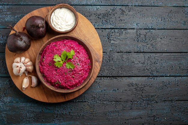 Bovenaanzicht bietensalade heerlijk binnen plaat met zure room en knoflook op donker bureau