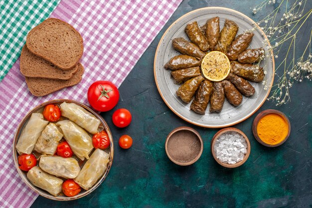 Bovenaanzicht blad dolma oosterse vleesmaaltijd gerold in groene bladeren met brood en kool dolma op het donkerblauwe bureau vlees diner schotel oostelijke maaltijd