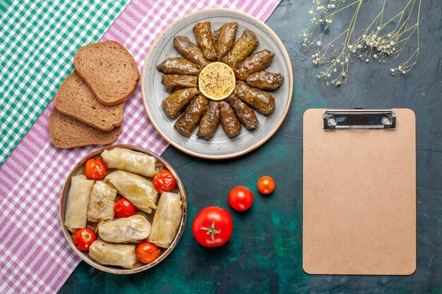 Bovenaanzicht blad dolma oosterse vleesmaaltijd gerold in groene bladeren met kool dolma en brood op donkerblauw bureau vlees diner schotel oost maaltijd calorie