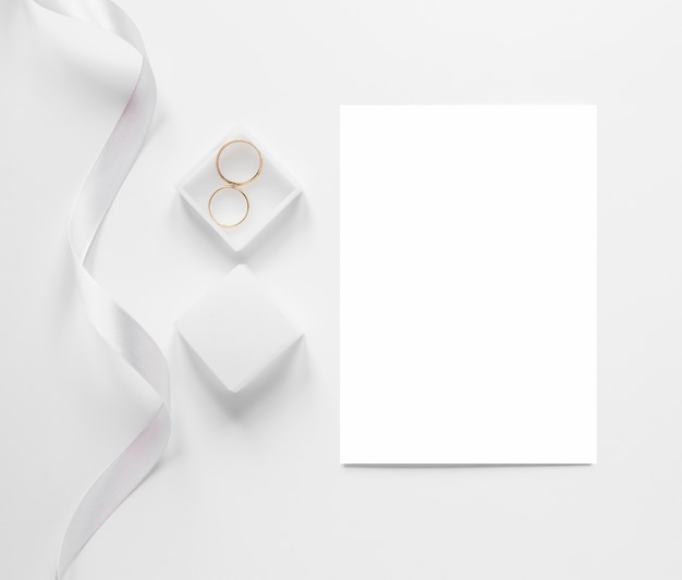 Bovenaanzicht blanco vel papier naast verlovingsringen