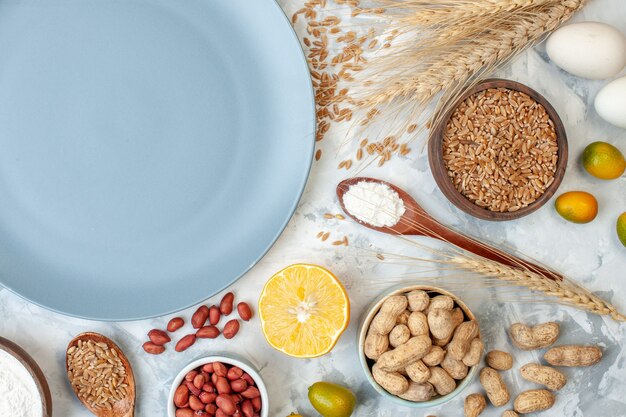 Bovenaanzicht blauw bord met meelgelei-eieren en verschillende noten op een deeg met witte suikerkleur, fruitfoto, taartnoot, zoete cake