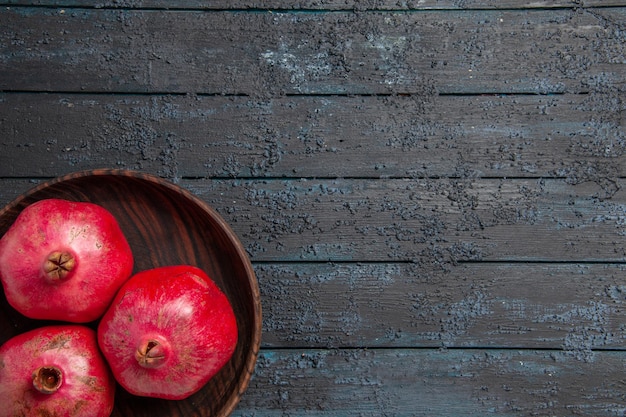 Bovenaanzicht bord met granaatappels bord met rijpe rode granaatappels aan de linkerkant van de tafel