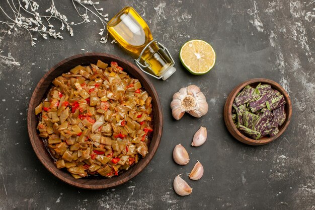 Bovenaanzicht bord met sperziebonen bord met sperziebonen en tomaten naast de fles olie knoflook en citroen op tafel