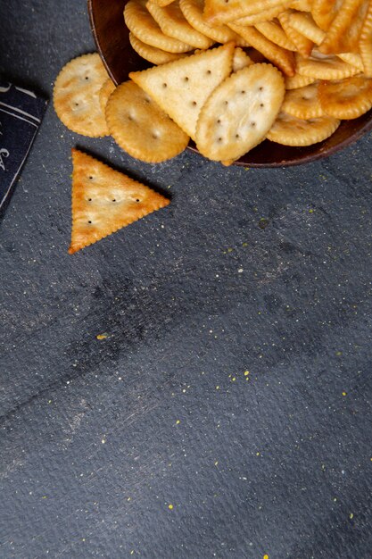 Bovenaanzicht bruine plaat met crackers op de grijze bureau scherpe cracker snackfoto