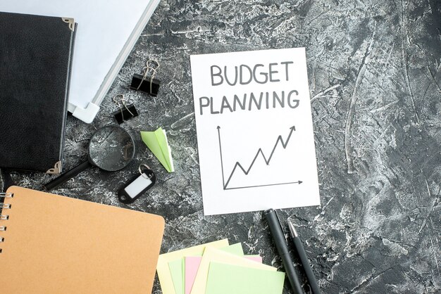 bovenaanzicht budgetplanning notitie met pennen op grijze ondergrond baan schrift school student bedrijf werk college geld budget
