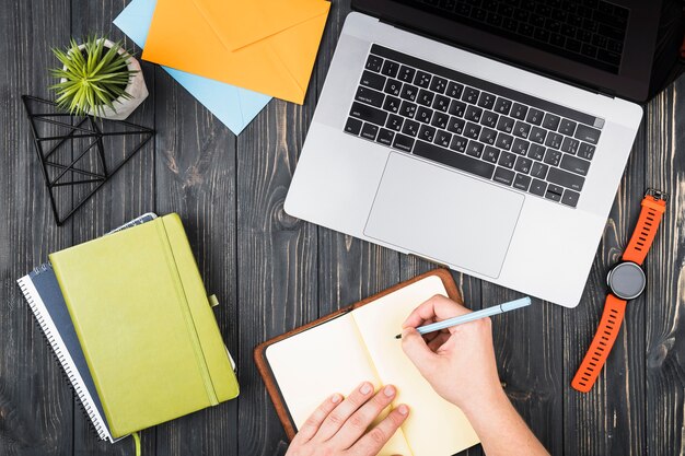 Bovenaanzicht bureau-arrangement met een persoon die schrijft