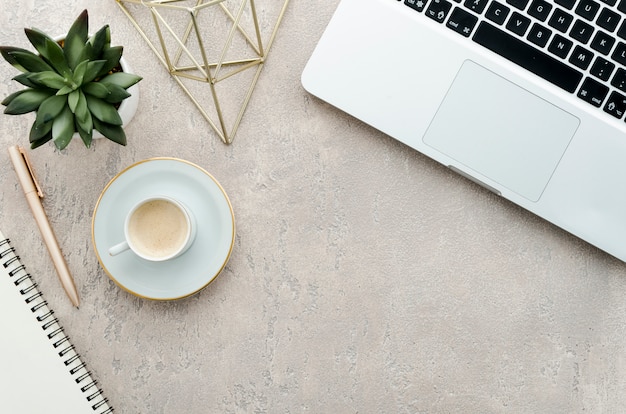 Bovenaanzicht bureau met koffie, plant en laptop