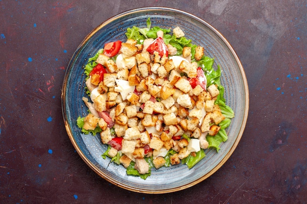 Bovenaanzicht caesar salade met gesneden groenten en beschuit op de donkere muur groentesalade eten lunch maaltijd beschuit smaak