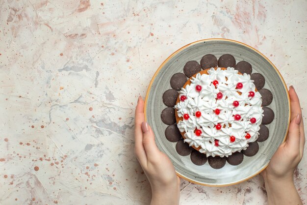 Bovenaanzicht cake met banketbakkersroom en chocolade in vrouwelijke hand