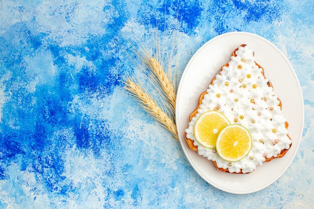 Bovenaanzicht cake met banketbakkersroom en citroen op plaat op blauwe tafel