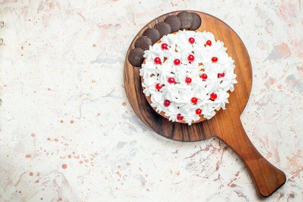 Bovenaanzicht cake met chocolade en witte banketbakkersroom op houten snijplank