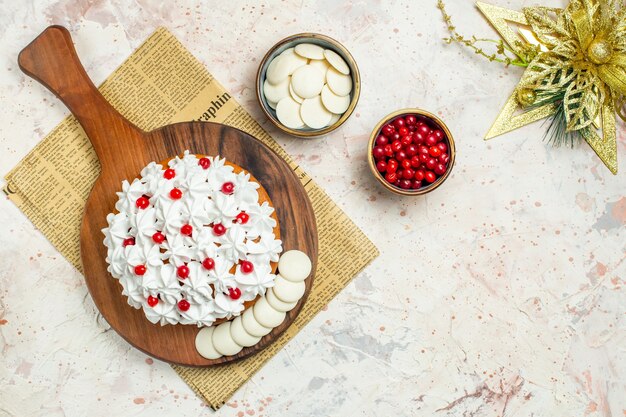 Bovenaanzicht cake met witte banketbakkersroom op een houten bord op krant. kerst ornament