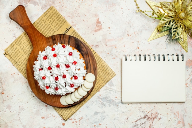 Bovenaanzicht cake met witte banketbakkersroom op een houten bord op krant. kerst ornament