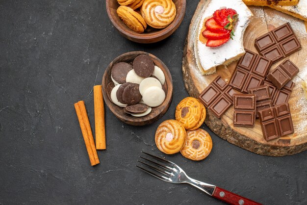 Bovenaanzicht cakeplakken met koekjes en chocolade op donkere achtergrond