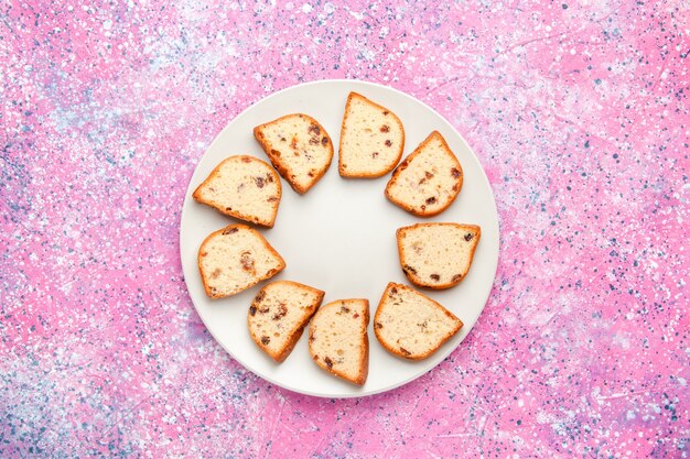 Bovenaanzicht cakeplakken met rozijnen in plaat op de roze achtergrond cake bakken zoete biscuit kleur taart suiker koekjes