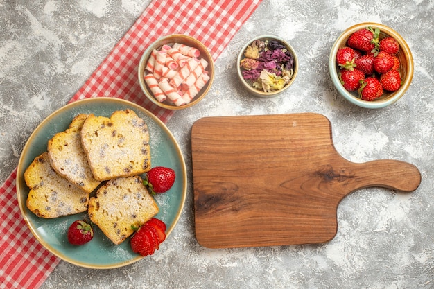 Bovenaanzicht cakeplakken met verse aardbeien op wit oppervlak zoete taart fruit