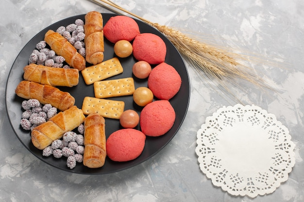 Gratis foto bovenaanzicht cakes en bagels met snoepjes en crackers in plaat op witte achtergrond cake biscuit cookie suiker zoete taart