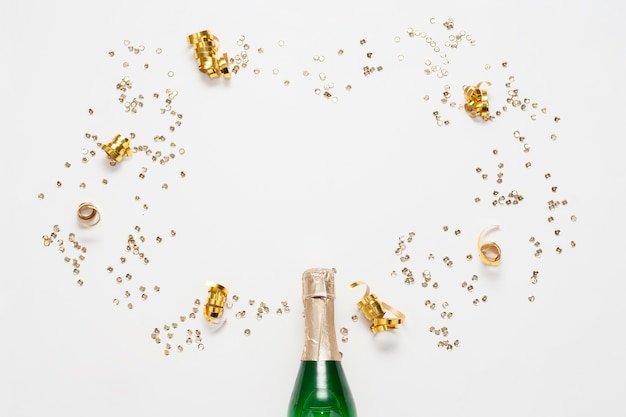 Bovenaanzicht champagnefles met gouden linten en confetti