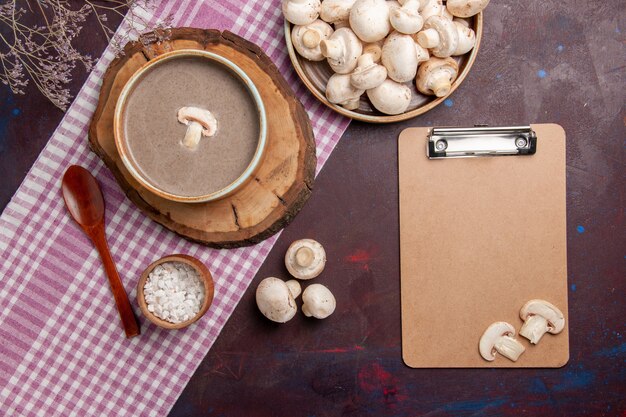 Bovenaanzicht champignonsoep met verse champignons op de donkere ruimte