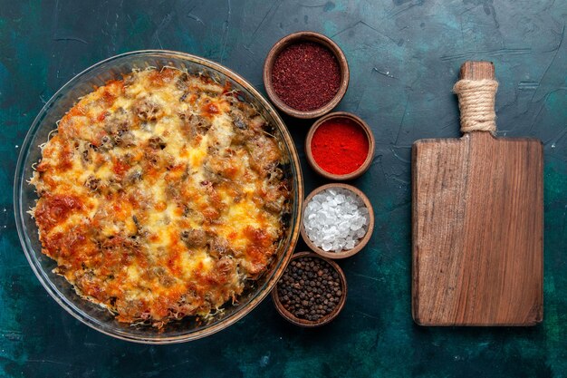 Bovenaanzicht cheesy vleesmaaltijd lekker bakken met kruiden op donkerblauw bureau eten vleesmaaltijd schotel plantaardig diner