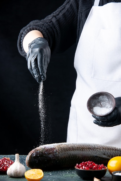Gratis foto bovenaanzicht chef-kok met handschoenen bestrooid met zout op verse vis granaatappel zaden in kom op tafel