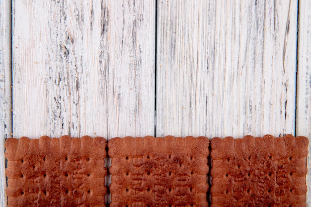 Bovenaanzicht chocolade crackers aan de onderkant met kopie ruimte op witte houten achtergrond