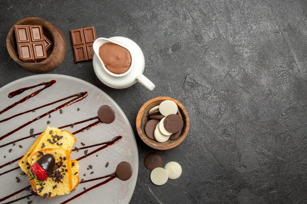 Bovenaanzicht chocolade op tafel kommen chocolade en chocoladeroom naast het bord cake met aardbeien en chocolade op tafel