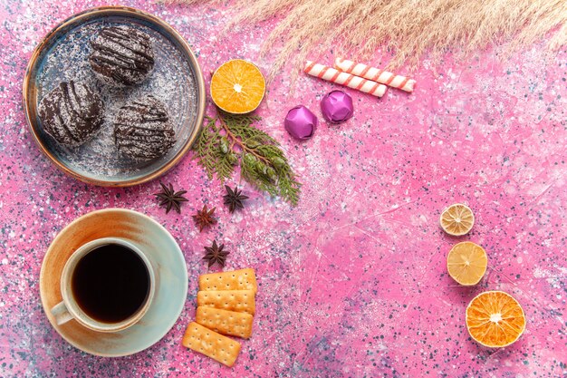 Bovenaanzicht chocoladecake met kopje thee op roze bureau