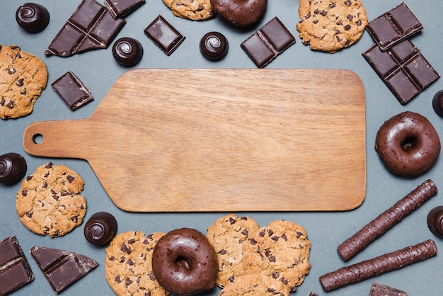 Gratis foto bovenaanzicht chocoladesuikergoed rond een snijplank