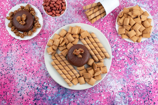 Bovenaanzicht chocoladetaart samen met crackers en koekjes op de kleurrijke achtergrond koekjeskoekje suiker zoete kleur