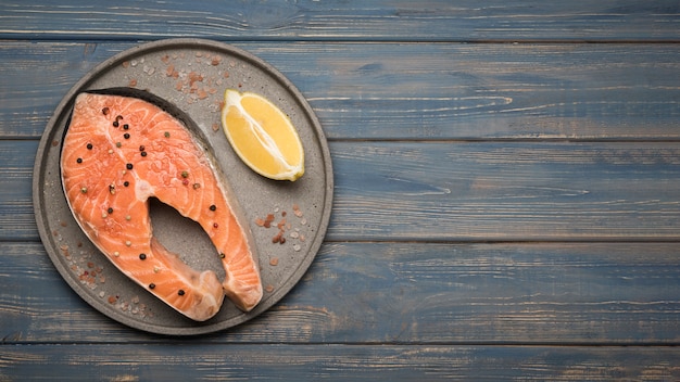 Bovenaanzicht citroen en zalm steak op dienblad met kopie-ruimte