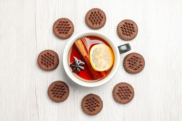 Bovenaanzicht citroen-kaneelthee afgerond met koekjes op de witte houten tafel