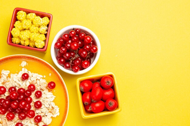 Bovenaanzicht close-up bessen havermout met rode aalbessen bessen snoepjes op de gele tafel
