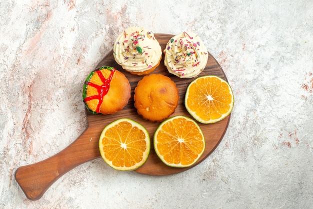 Bovenaanzicht cookies smakelijke koekjes en citrusvruchten op de snijplank op het lichte oppervlak