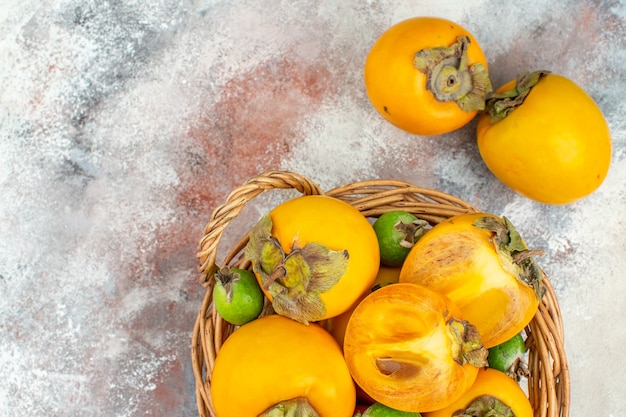 Gratis foto bovenaanzicht delicios kaki feykhoas in rieten mand op naakte achtergrond