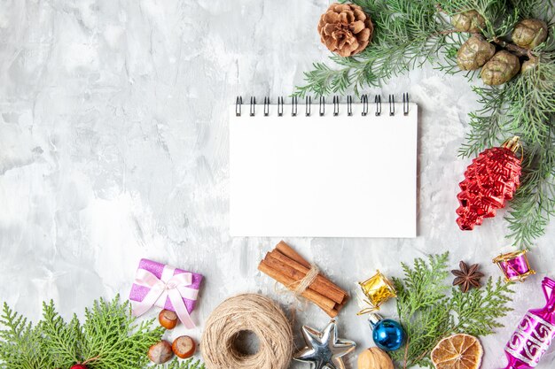 Bovenaanzicht dennenboom takken kegels kerstboom speelgoed kaneelstokjes anijs notebook op grijze achtergrond