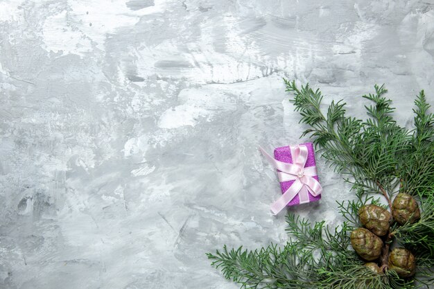 Bovenaanzicht dennenboom takken klein cadeautje op grijze ondergrond