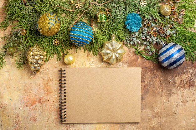 Bovenaanzicht dennentakken kerstboom versieringen een notitieboekje op beige achtergrond