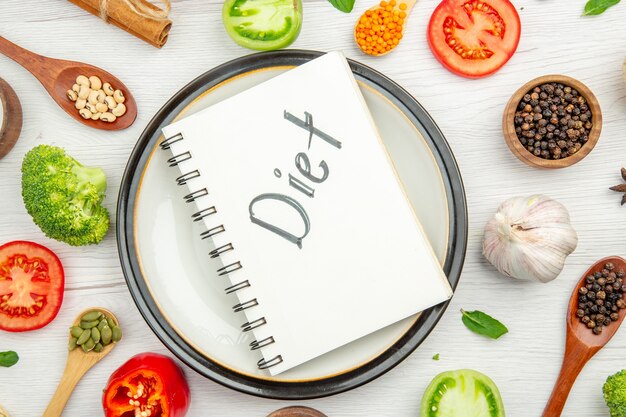 Bovenaanzicht dieet geschreven op Kladblok op bord met groenten op grijze tafel