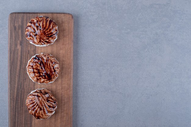 Bovenaanzicht. Drie vers koekje op een houten bord