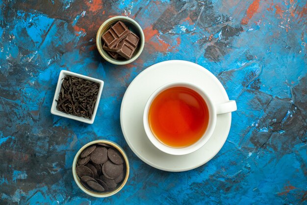 Bovenaanzicht een kopje thee chocolaatjes in kleine kommetjes op blauw rood oppervlak