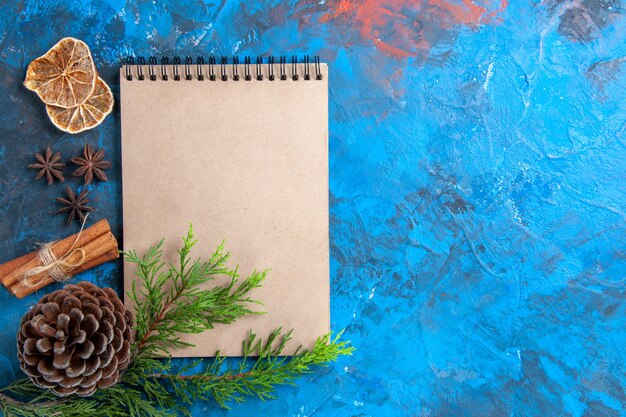 Bovenaanzicht een notebook dennenboom takken dennenappel steranijs op blauwe achtergrond vrije ruimte