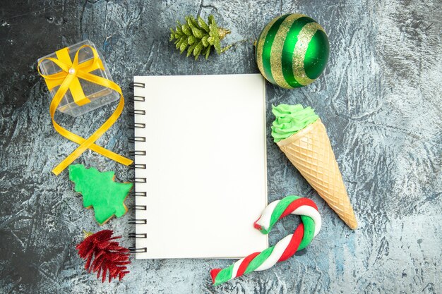 Bovenaanzicht een notebook xmas snoepjes en speelgoed op grijze achtergrond