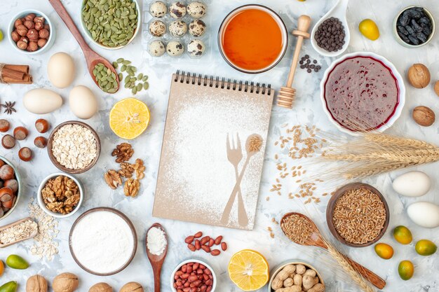 Bovenaanzicht eenvoudig notitieblok met eieren meel gelei en verschillende noten op witte noten suiker kleur taart foto deeg fruit zoete cake