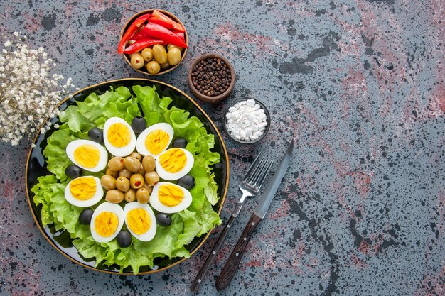 bovenaanzicht eiersalade bestaat uit groene salade en olijven op lichte achtergrond