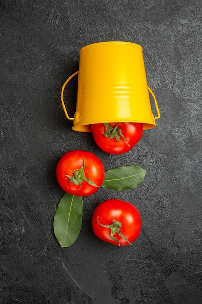 Bovenaanzicht emmer met rode tomaten op donkere achtergrond