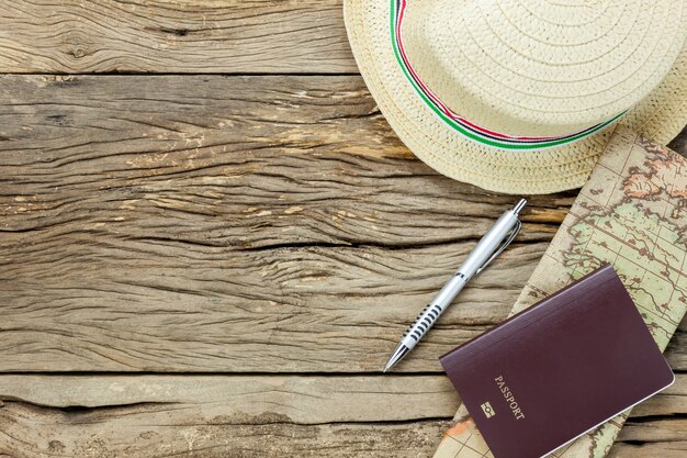 Bovenaanzicht essentiële punten om te reizen. De kaart paspoort hoed op rustieke houten achtergrond.