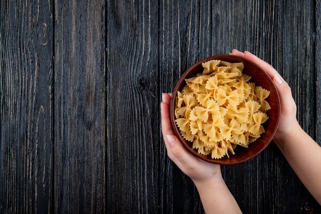 Bovenaanzicht farfalle pasta aan de rechterkant met kopie ruimte op zwarte houten achtergrond